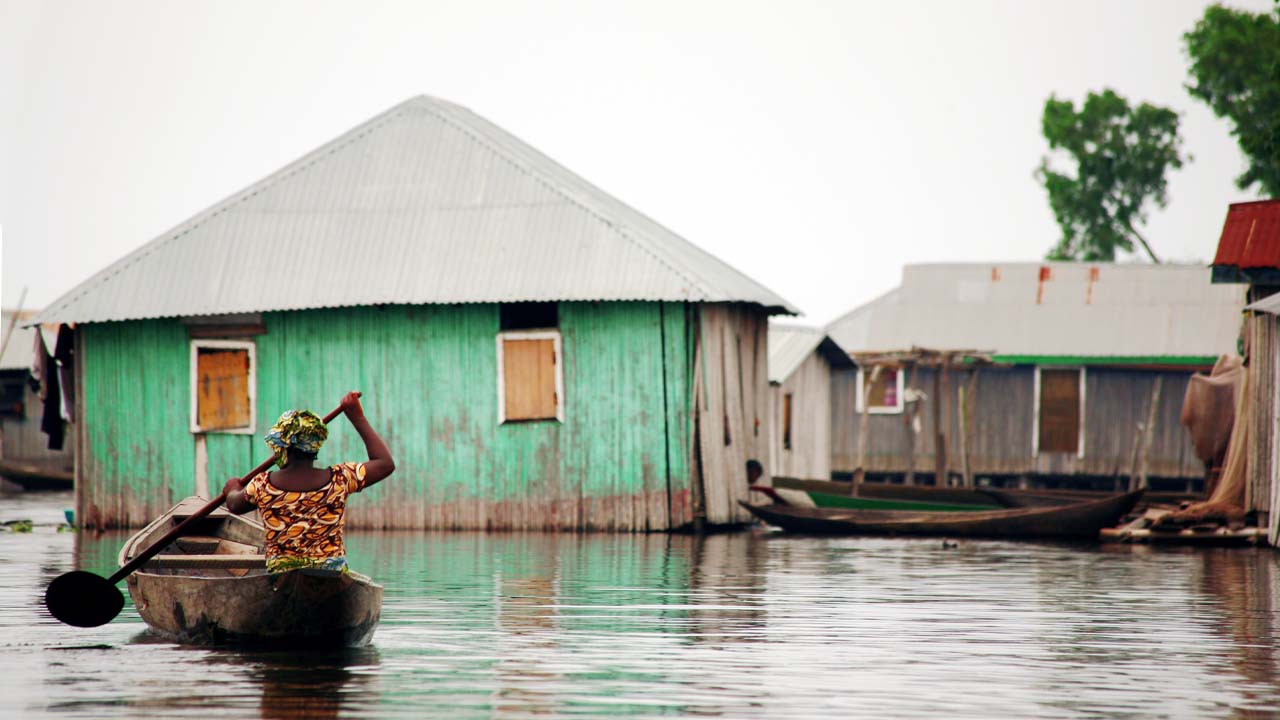 Woman in canoe in a  flooded vilage